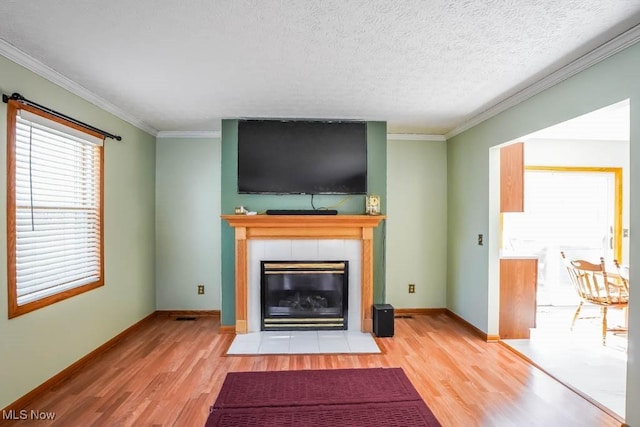 unfurnished living room with wood-type flooring, ornamental molding, and a tile fireplace