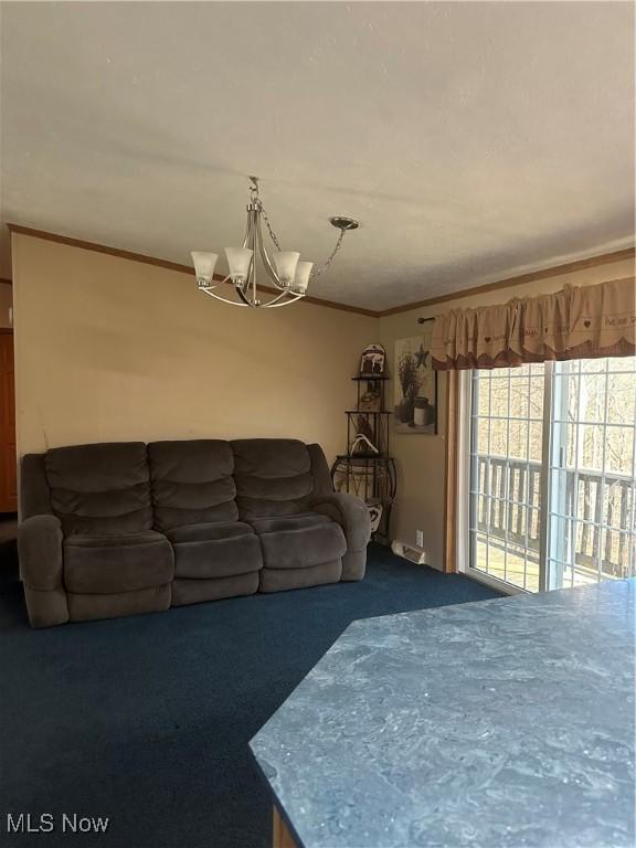 living room featuring a notable chandelier, ornamental molding, and carpet flooring