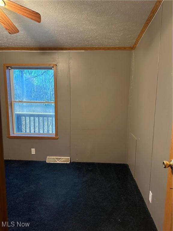 carpeted spare room with ceiling fan and a textured ceiling