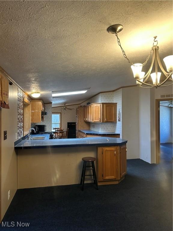 kitchen featuring a kitchen breakfast bar, decorative light fixtures, kitchen peninsula, and a textured ceiling