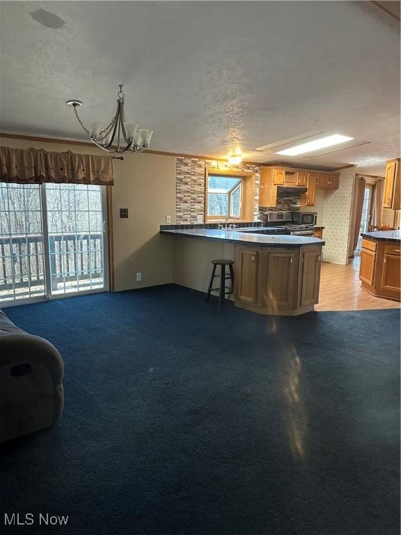 kitchen with light carpet, a notable chandelier, kitchen peninsula, and a textured ceiling