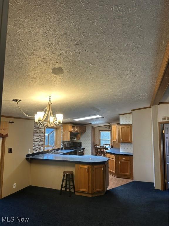 kitchen featuring an inviting chandelier, decorative light fixtures, kitchen peninsula, and a textured ceiling