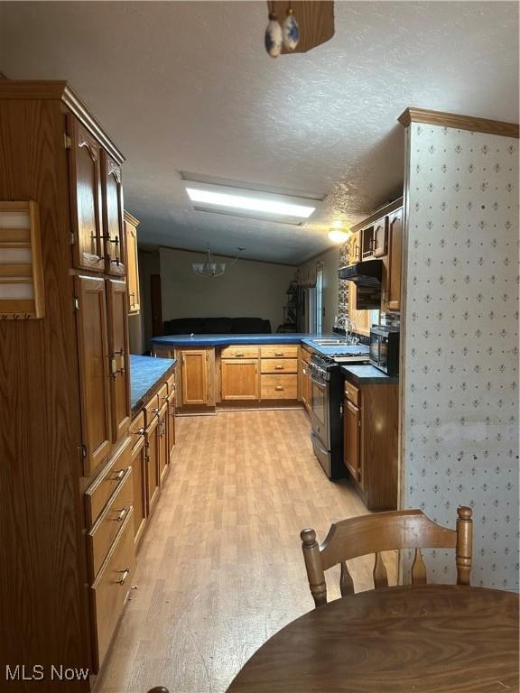 kitchen featuring sink, black range oven, light hardwood / wood-style flooring, a textured ceiling, and kitchen peninsula