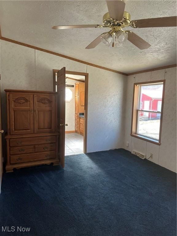 spare room with crown molding, ceiling fan, carpet flooring, and a textured ceiling