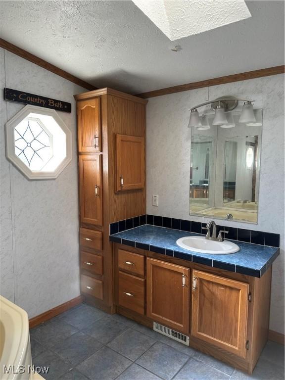 bathroom with vanity, ornamental molding, and a textured ceiling