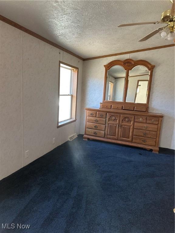 unfurnished bedroom featuring crown molding, carpet, ceiling fan, and a textured ceiling