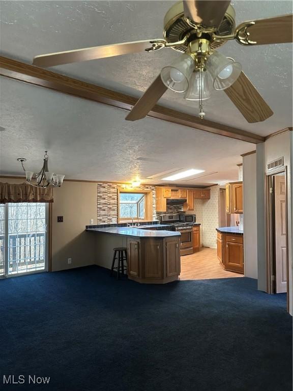 kitchen with stainless steel appliances, kitchen peninsula, light carpet, and a textured ceiling