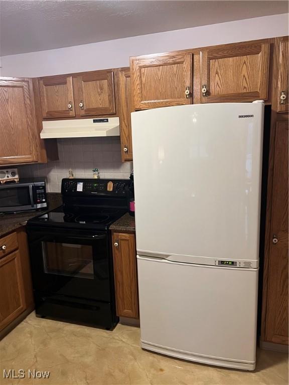 6695 Clingan Rd Unit 26, Poland, OH 44514 - kitchen with freestanding refrigerator, electric range, under cabinet range hood, stainless steel microwave, and dark countertops