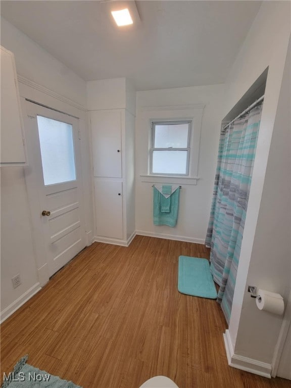 bathroom with a shower with curtain, baseboards, and wood finished floors