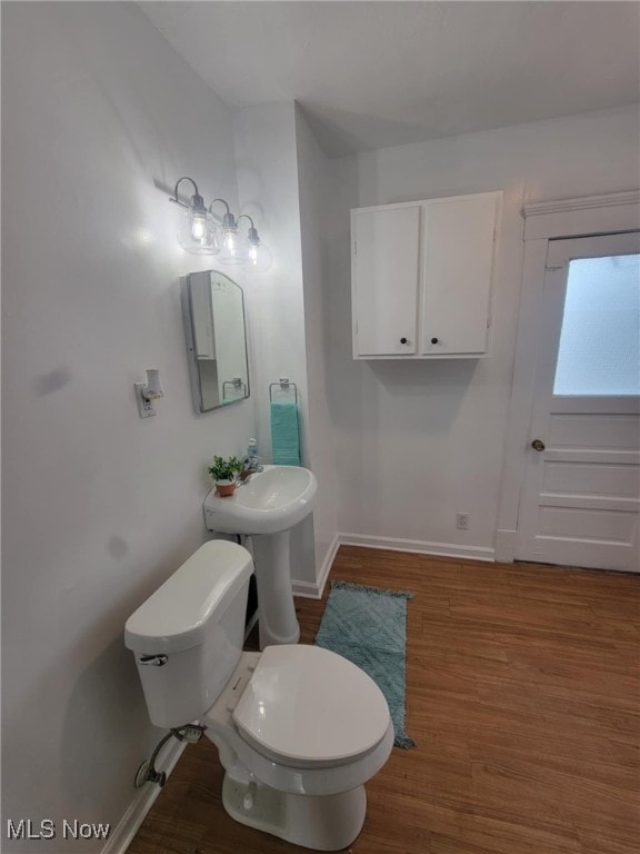 bathroom with wood finished floors, toilet, and baseboards