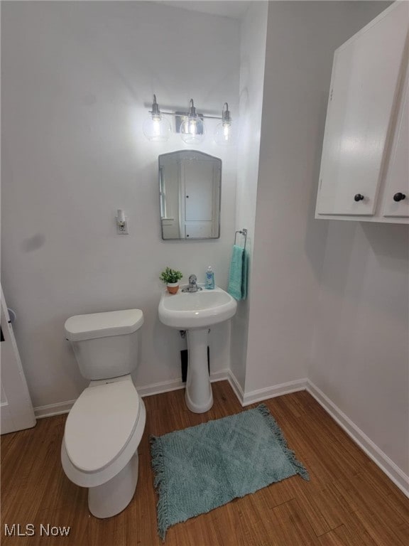 bathroom featuring wood finished floors, toilet, and baseboards