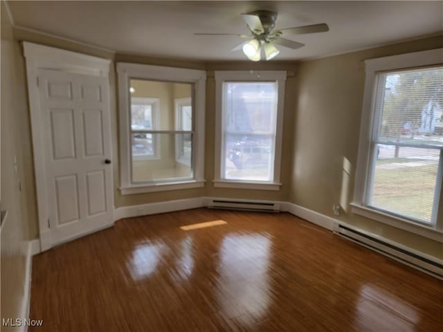 unfurnished dining area featuring a baseboard heating unit, a wealth of natural light, and wood finished floors