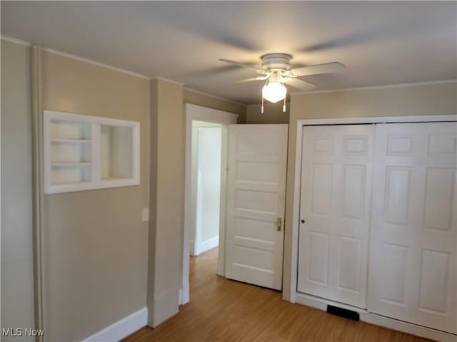 unfurnished bedroom with ornamental molding, a closet, light wood-style floors, and baseboards