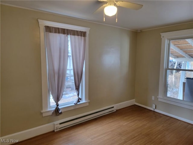 empty room featuring baseboard heating, light wood-style flooring, and baseboards