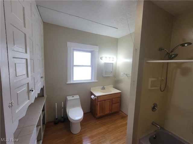 full bathroom with bathing tub / shower combination, vanity, toilet, and wood finished floors