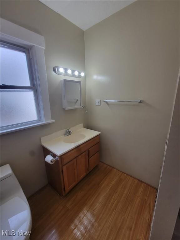 bathroom with toilet, wood finished floors, and vanity