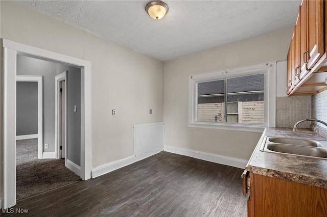 kitchen featuring sink, a textured ceiling, backsplash, and dark hardwood / wood-style flooring