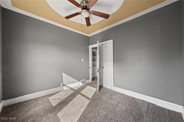 unfurnished room featuring a raised ceiling, carpet, and ceiling fan