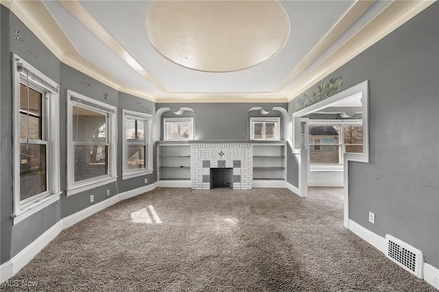 carpeted spare room featuring a tray ceiling and a fireplace