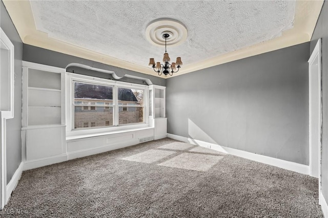 carpeted spare room with a textured ceiling and an inviting chandelier