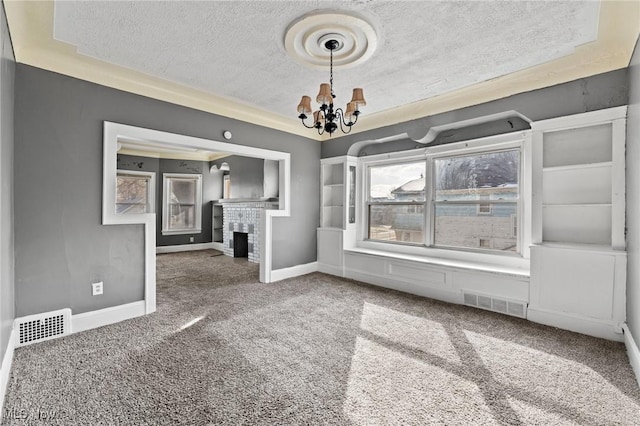 unfurnished living room with a textured ceiling, a fireplace, a chandelier, and carpet flooring