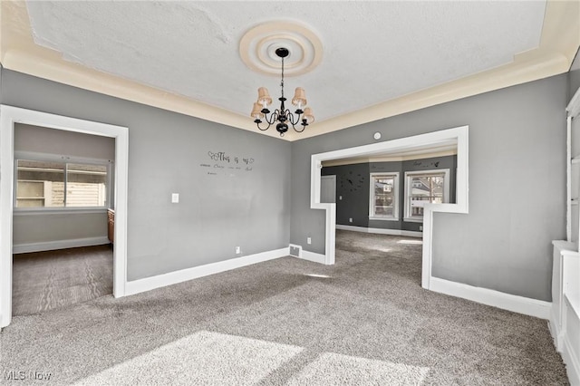 spare room with carpet floors, a textured ceiling, and a chandelier