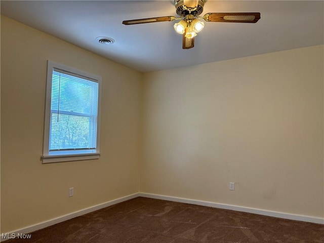 spare room featuring dark colored carpet and ceiling fan