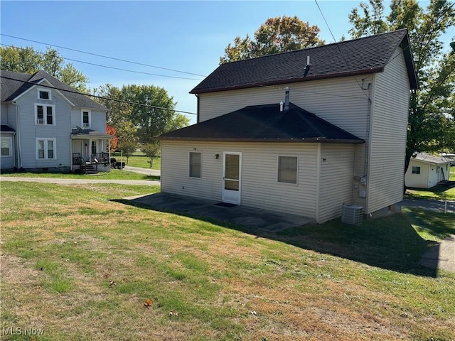 rear view of property featuring central AC unit and a lawn