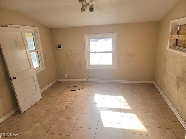 spare room featuring vaulted ceiling and light tile patterned floors