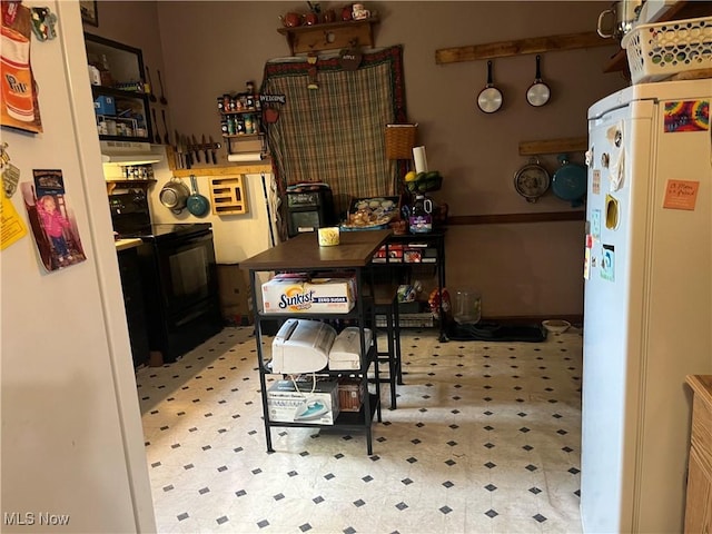 kitchen with white fridge and black range with electric cooktop