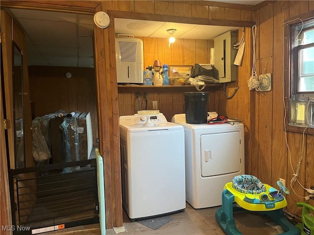 laundry room featuring separate washer and dryer, wooden walls, and light hardwood / wood-style floors