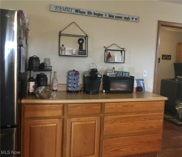 bar with stainless steel refrigerator and dark wood-type flooring