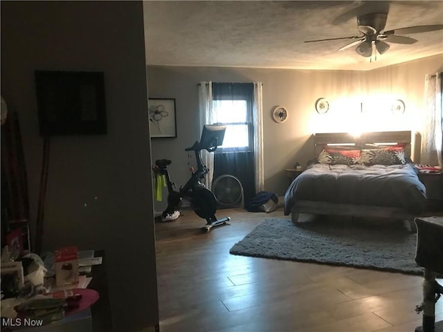 bedroom with ceiling fan, hardwood / wood-style floors, and a textured ceiling