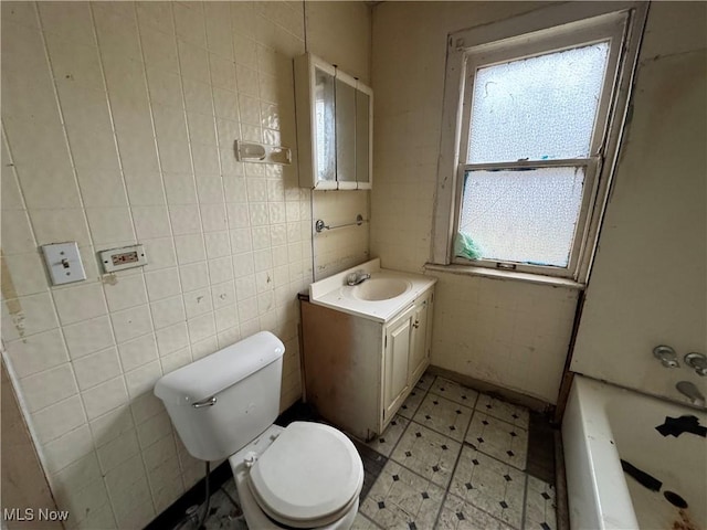 bathroom with vanity, toilet, tile walls, and a washtub