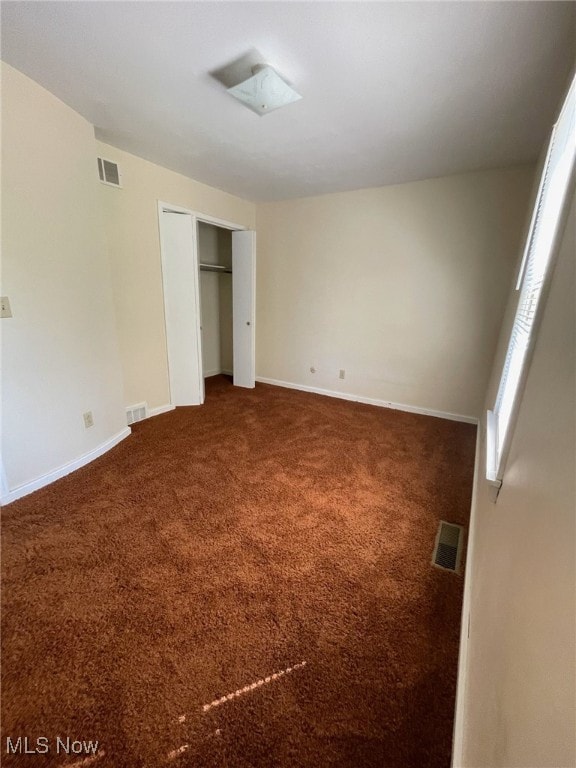 unfurnished bedroom with dark carpet and a closet