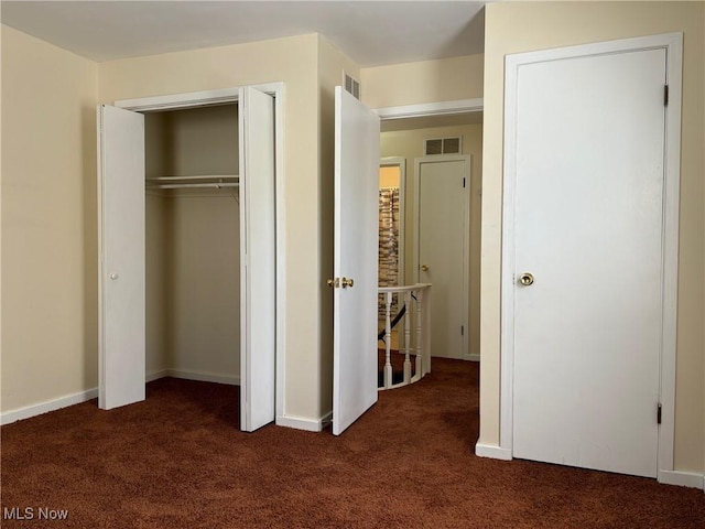 unfurnished bedroom featuring a closet and dark colored carpet