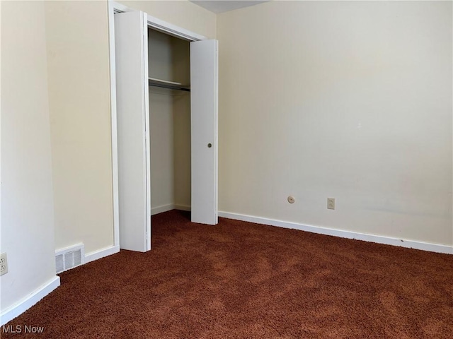 unfurnished bedroom featuring a closet and dark colored carpet