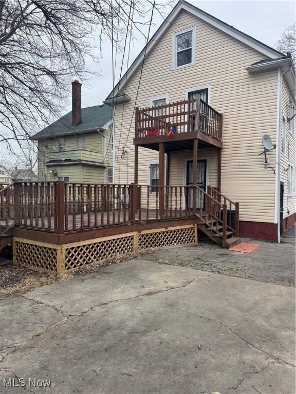 back of property featuring a wooden deck and a patio