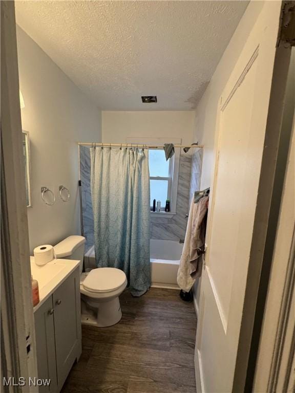 full bathroom featuring toilet, wood-type flooring, a textured ceiling, vanity, and shower / bath combo