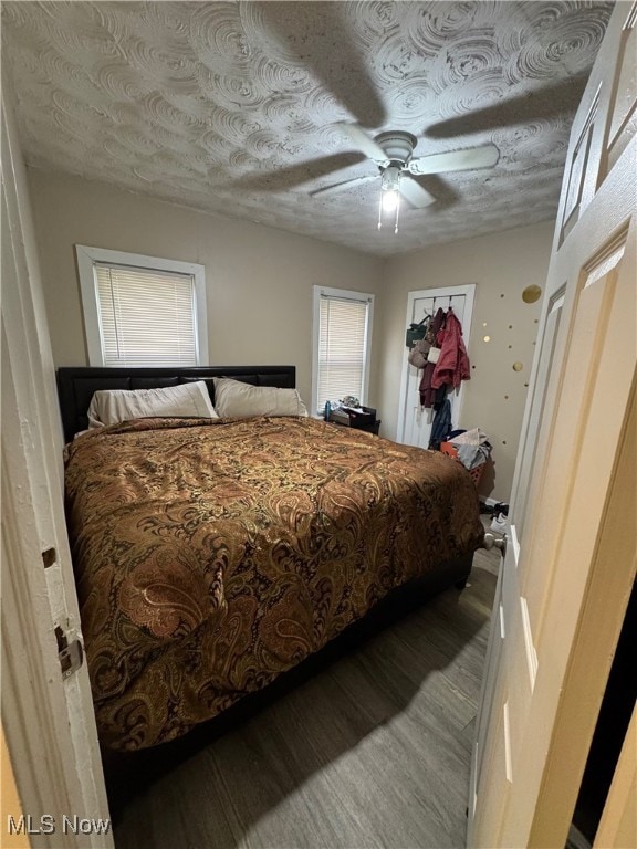 bedroom with ceiling fan, wood-type flooring, and a textured ceiling