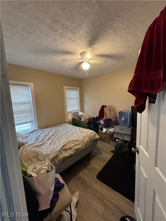 bedroom with ceiling fan, a textured ceiling, and light hardwood / wood-style floors