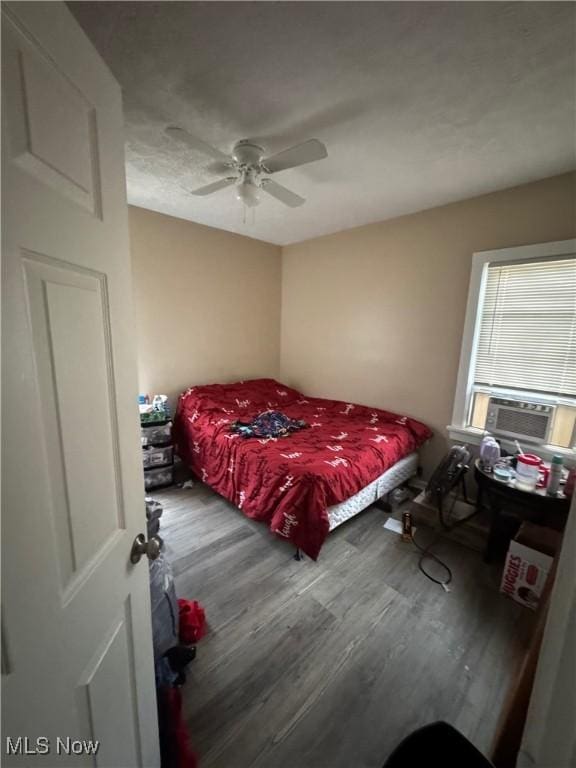 bedroom featuring cooling unit, ceiling fan, and hardwood / wood-style floors