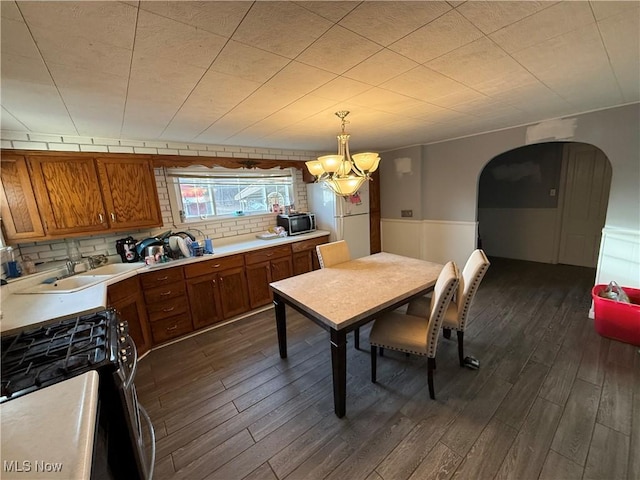 dining room with sink, dark wood-type flooring, and a chandelier