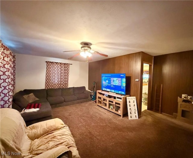 living room with wooden walls, ceiling fan, and carpet flooring