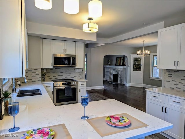 kitchen featuring pendant lighting, white cabinetry, appliances with stainless steel finishes, and a fireplace