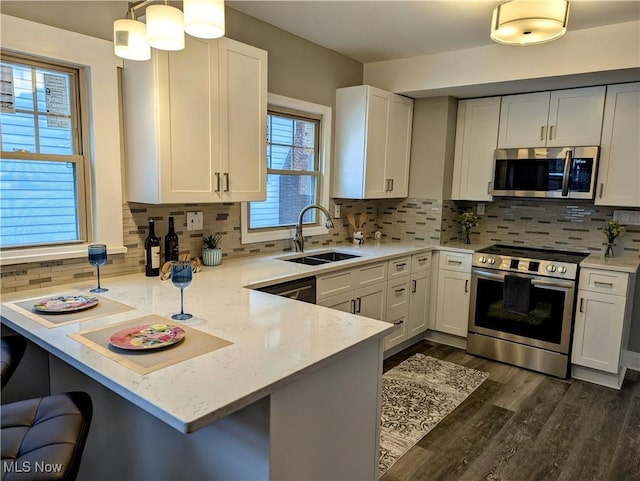 kitchen featuring sink, appliances with stainless steel finishes, hanging light fixtures, a kitchen breakfast bar, and kitchen peninsula