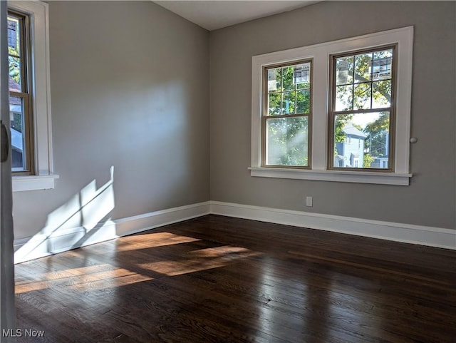 empty room featuring dark wood-type flooring and baseboards