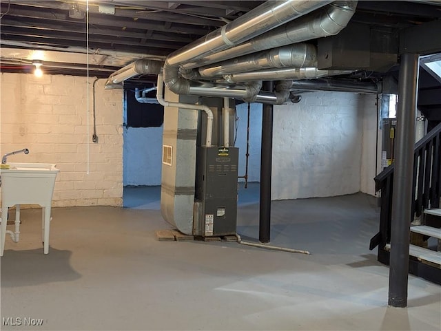 unfinished below grade area with heating unit, stairway, and a sink