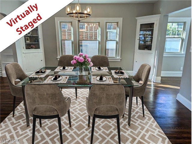 dining area with baseboards, wood finished floors, and a notable chandelier