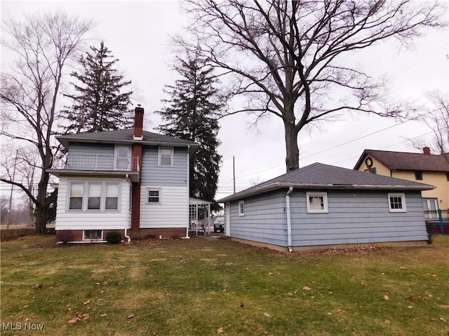 rear view of property with a lawn and a balcony